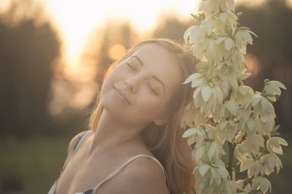 Portrait en gros plan.. Jeune belle jolie femme posant en robe longue contre dans le domaine avec des fleurs blanches — Photo