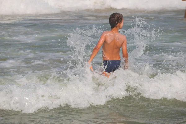 Picture of exciting boy running on beach beside waves. image of kid in evening sunlights on seaside background. — Stock Photo, Image