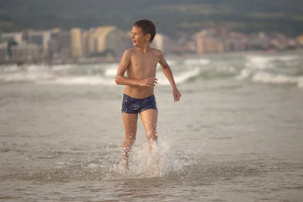 Boy frolics in the sea with splashes and waves — Stock Photo, Image