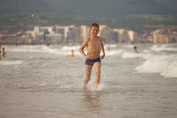 Boy frolics in the sea with splashes and waves — Stock Photo, Image