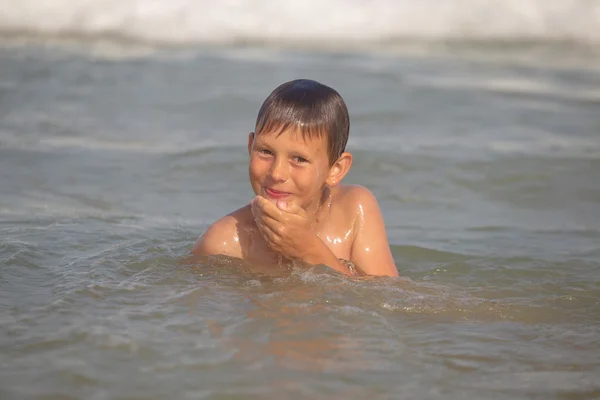 Chłopiec igraszek w morzu z plamami i fale — Zdjęcie stockowe