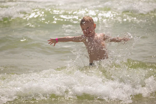 Chłopiec igraszek w morzu z plamami i fale — Zdjęcie stockowe