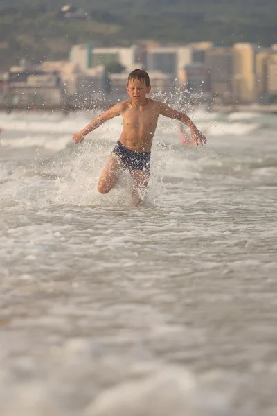 Boy frolics in the sea with splashes and waves — Stock Photo, Image