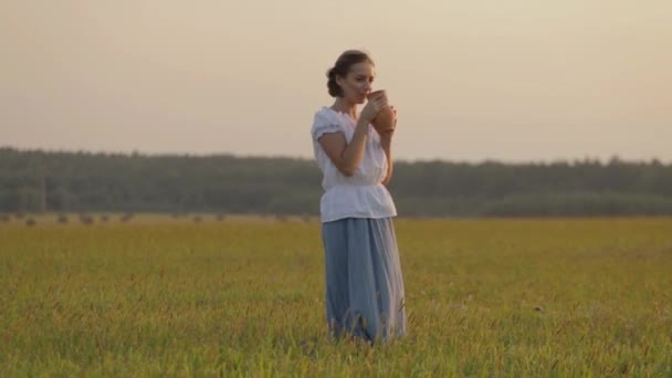 Mooi meisje is het drinken van melk van een kruik op de natuur — Stockvideo