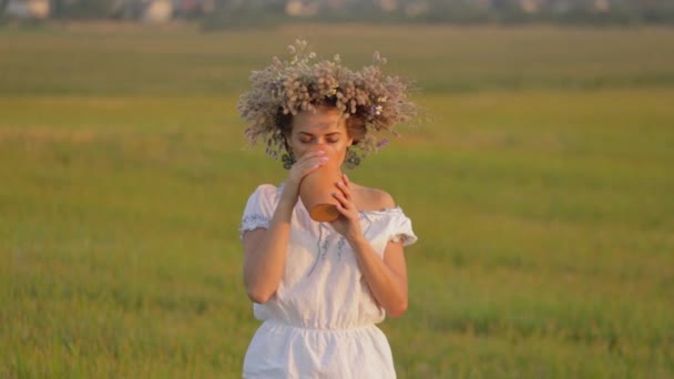 Giovane bella ragazza sta bevendo latte da una brocca sulla natura — Video Stock