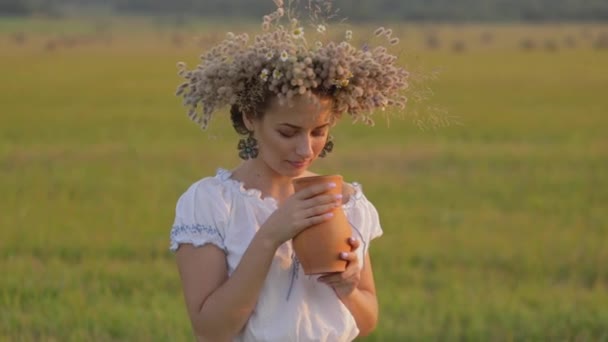 Mooi meisje is het drinken van melk van een kruik op de natuur — Stockvideo