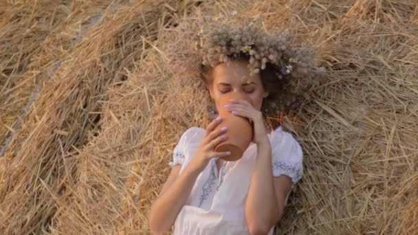 Jovem menina bonita está bebendo leite de um jarro na natureza — Vídeo de Stock