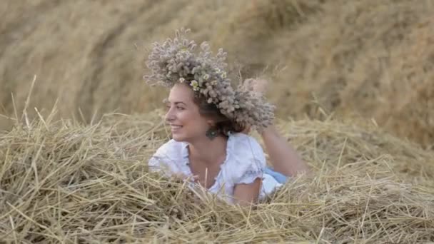 Young girl in a wreath resting in straw haystack — Stock Video