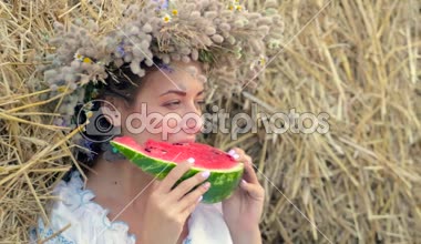 genç kız bir çelenk içinde saman yığını yakınındaki karpuz yiyor