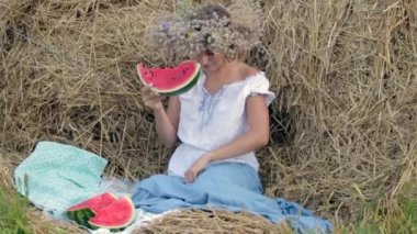 genç kız bir çelenk içinde saman yığını yakınındaki karpuz yiyor