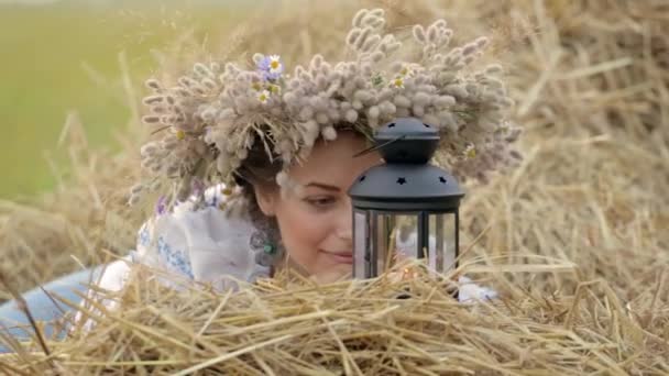 一个年轻的姑娘，头戴皇冠着附近的稻草堆灯笼. — 图库视频影像