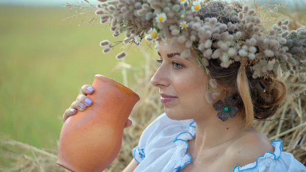 Joven hermosa chica es beber leche de una jarra en la naturaleza — Foto de Stock