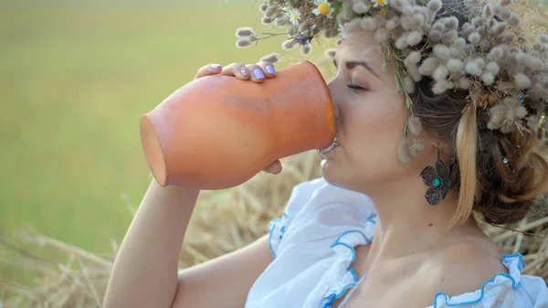 Jovem menina bonita está bebendo leite de um jarro na natureza — Fotografia de Stock