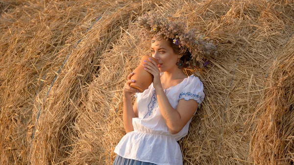 Молода красива дівчина п'є молоко з глечика на природі — стокове фото