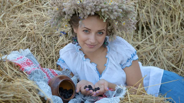 Giovane ragazza in una ghirlanda che riposa in paglia pagliaio — Foto Stock