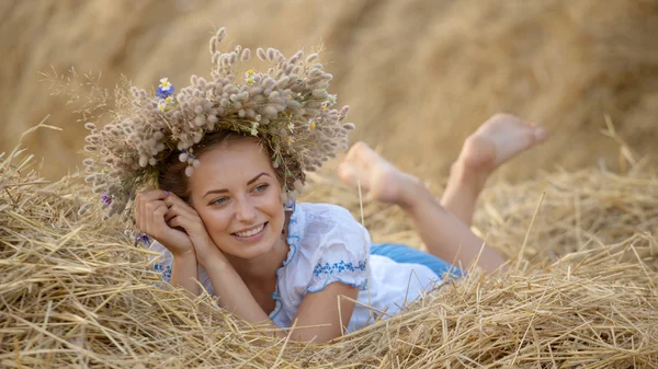 Ung flicka i en krans som vilar i halm höstack — Stockfoto