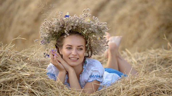 わら干し草で休んでいる花輪の少女 — ストック写真