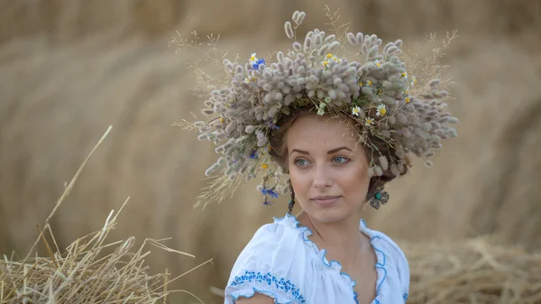 Giovane ragazza in una ghirlanda che riposa in paglia pagliaio — Foto Stock