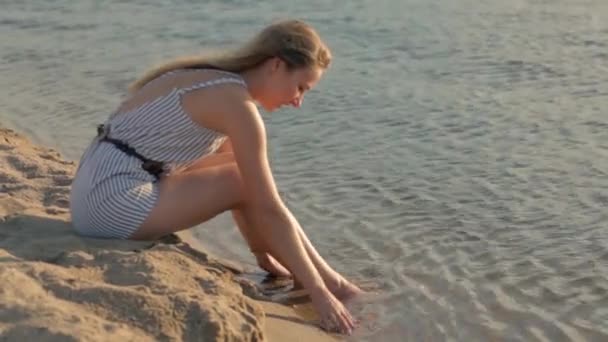 Girl resting on the sand near the river in the evening — Stock Video