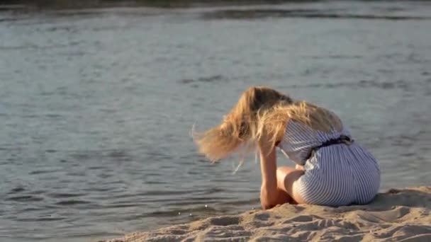 Menina descansando na areia perto do rio à noite — Vídeo de Stock