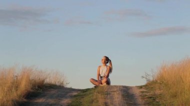 Güzel genç kız üzerinde batan güneşin ışınları Hill'de meditasyon