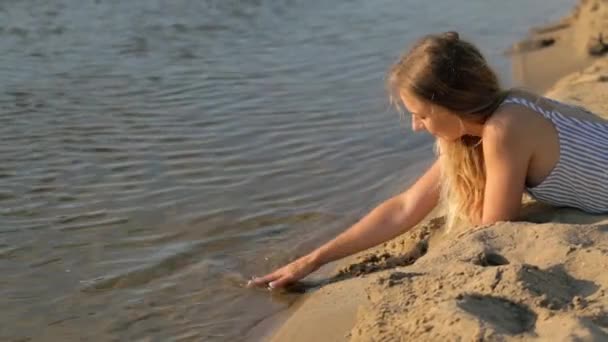 Fille se reposant sur le sable près de la rivière dans la soirée — Video