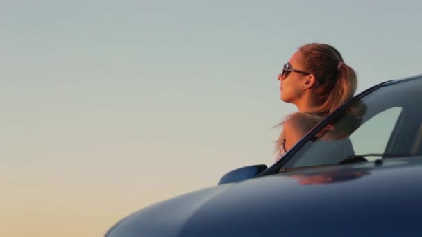 Menina bonita de pé no carro para o pôr do sol — Vídeo de Stock