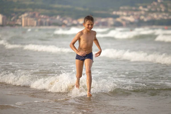 Boy frolics in the sea with splashes and waves — Stock Photo, Image