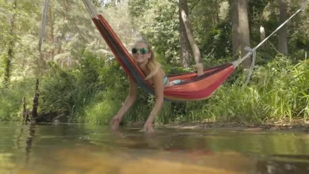 Bella ragazza cavalcando su un'amaca sopra l'acqua . — Video Stock