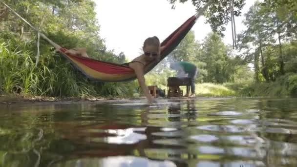 Vacker flicka ridning i en hängmatta över vattnet. — Stockvideo