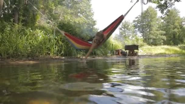 Hermosa chica cabalgando en una hamaca sobre el agua . — Vídeo de stock