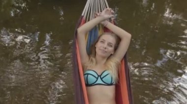 Kız bir hamakta su üzerinde yalan bir mayo içinde