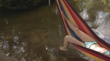 Kız bir hamakta su üzerinde yalan bir mayo içinde