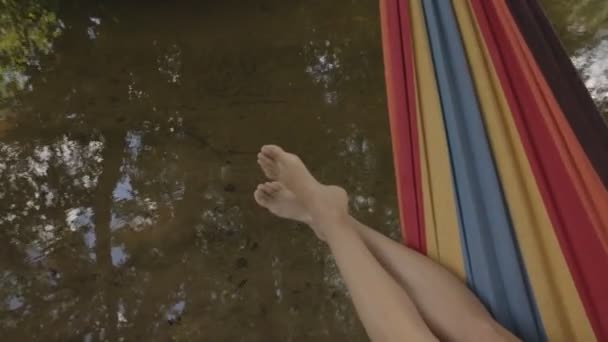 Dziewczyna w kostiumie kąpielowym, leżącego w hamaku nad wodą — Wideo stockowe