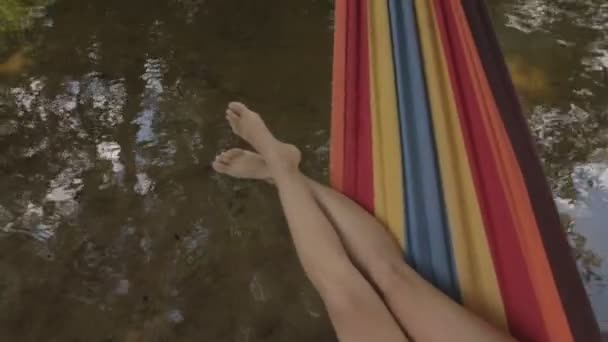Dívka v plavkách leží v houpací síti nad vodou — Stock video