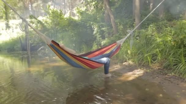 Meisje in een badpak liggend in een hangmat over het water — Stockvideo