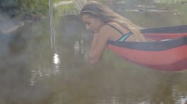 Kız bir hamakta su üzerinde yalan bir mayo içinde