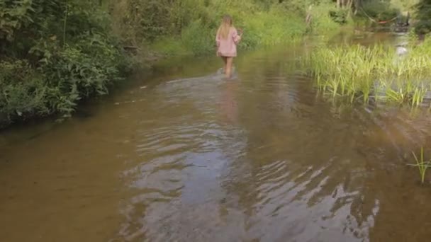Beautiful girl walking on the bank of forest river — Stock Video