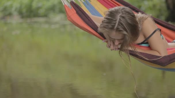 Vacker flicka ridning i en hängmatta över vattnet. — Stockvideo