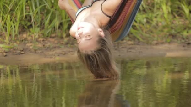 Ragazza sdraiata su un'amaca sopra il fiume, e i suoi capelli nell'acqua — Video Stock