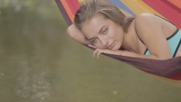 Beautiful girl riding in a hammock over the water. — Stock Video