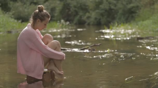 Mooi meisje mediteert over water in het midden van de rivier van de bos — Stockvideo