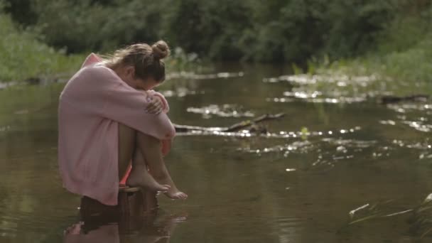 Vacker flicka mediterar på vatten mitt i floden skog — Stockvideo