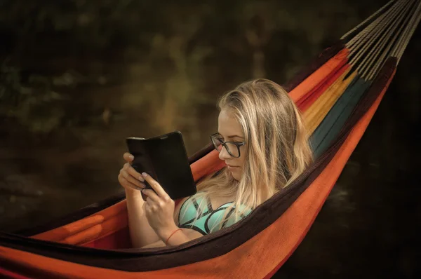 Flicka i en hängmatta med en telefon i handen — Stockfoto
