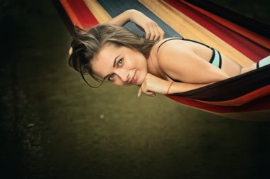 Kız bir hamakta su üzerinde yalan bir mayo içinde