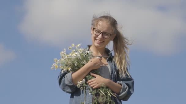 Menina com um buquê de margaridas em um fundo de céu azul — Vídeo de Stock