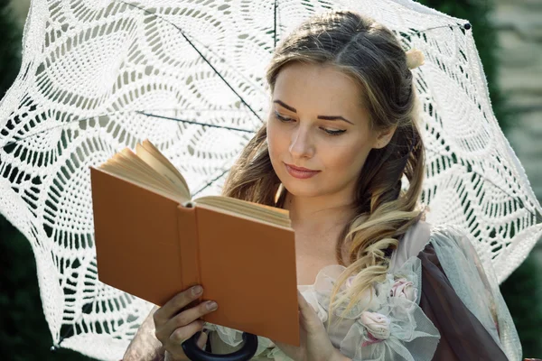 Meisje het lezen van een boek terwijl je onder een paraplu — Stockfoto