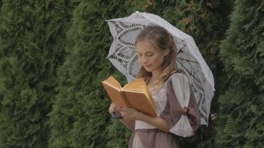 Kız bir şemsiye altında duran bir kitap okuma.