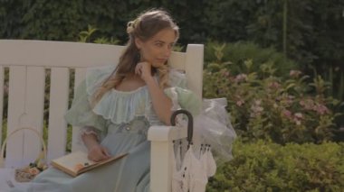 Kız bir bankta yaz öğleden sonra bir kitap okuma