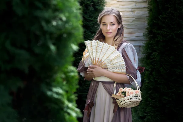 Meisje met een ventilator en een mandje op een groene achtergrond — Stockfoto